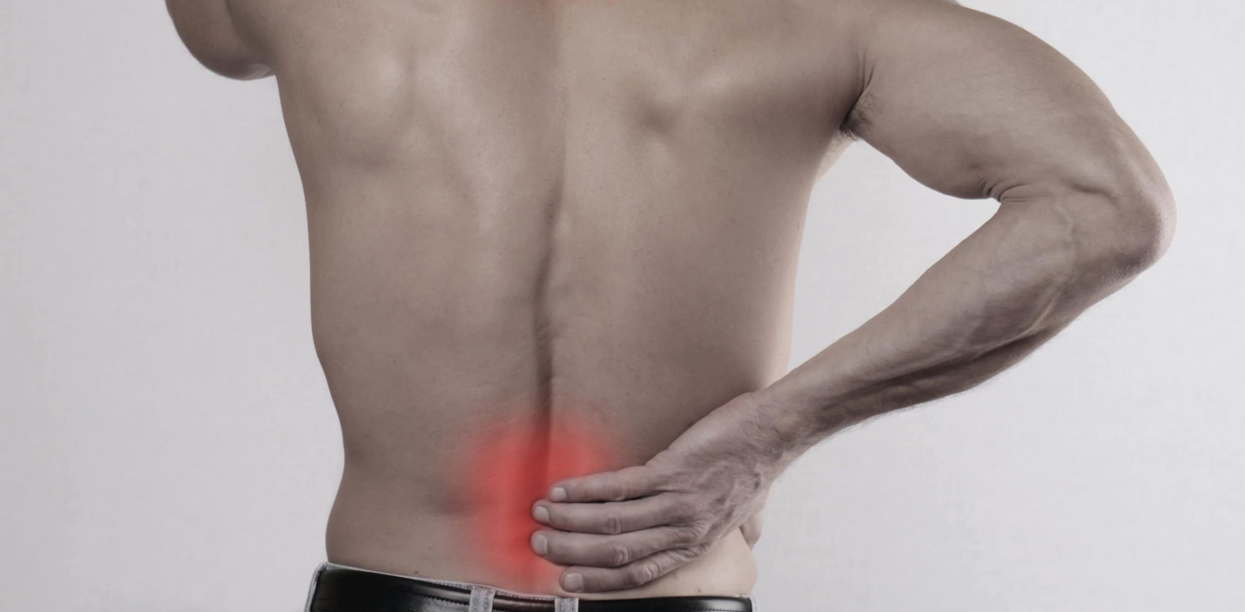 Back view of shirtless man clutching lower back with red highlighted pain area.