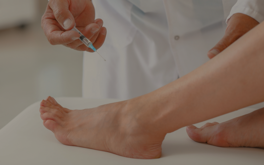 Medical professional administering an injection into a patient’s ankle/foot.