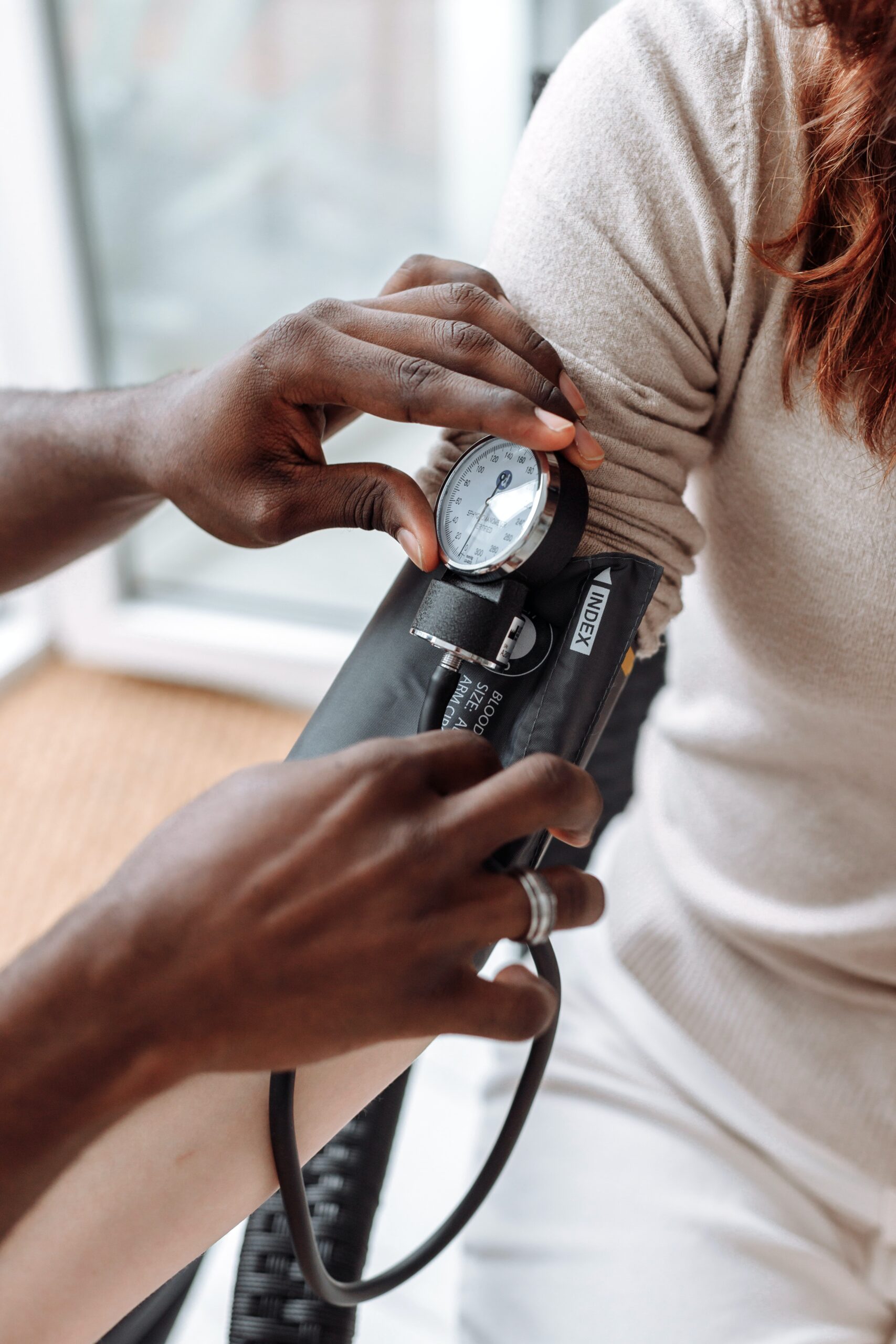 Person’s arm with a clinician using a sphygmomanometer to measure blood pressure.