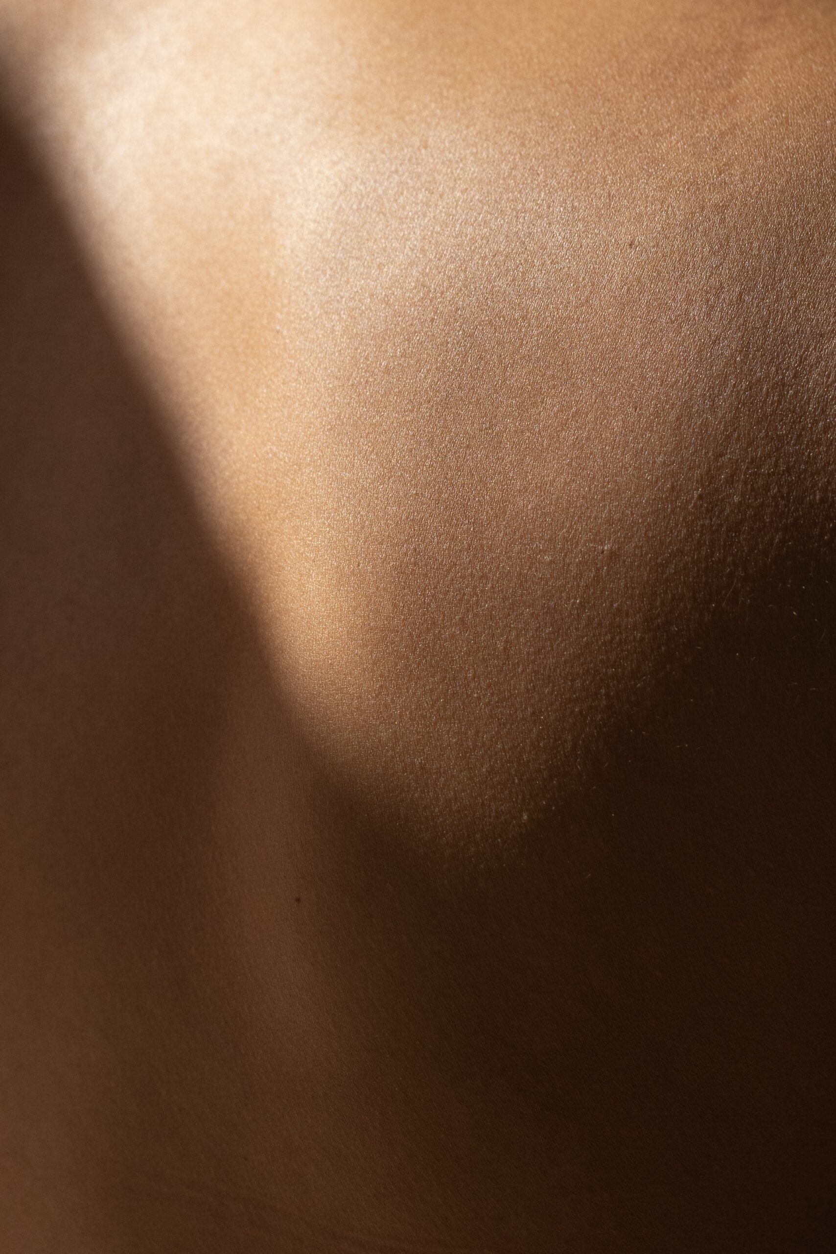 Close-up of bronze-toned skin with subtle highlights and shadows.