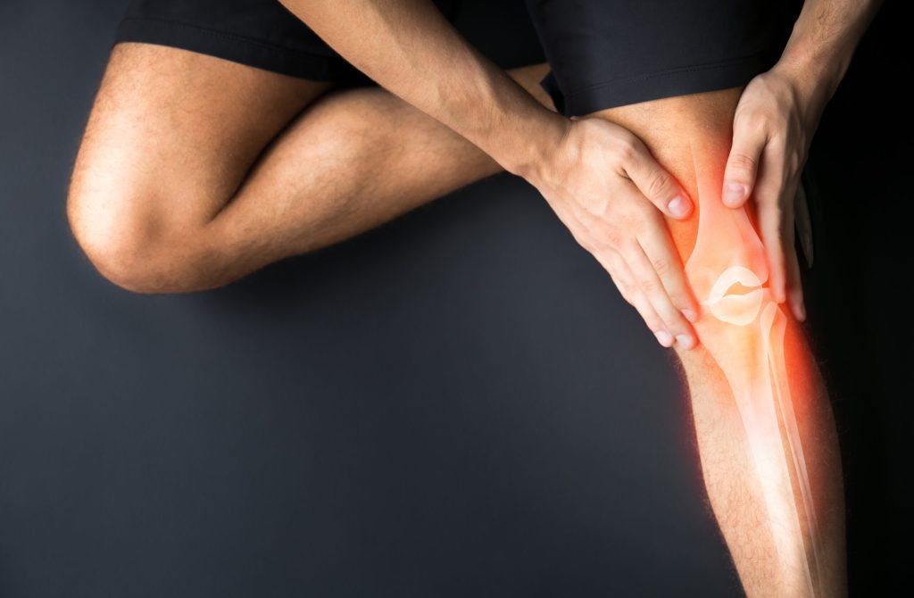 Person holding knee with highlighted knee joint/X-ray overlay on a dark background.