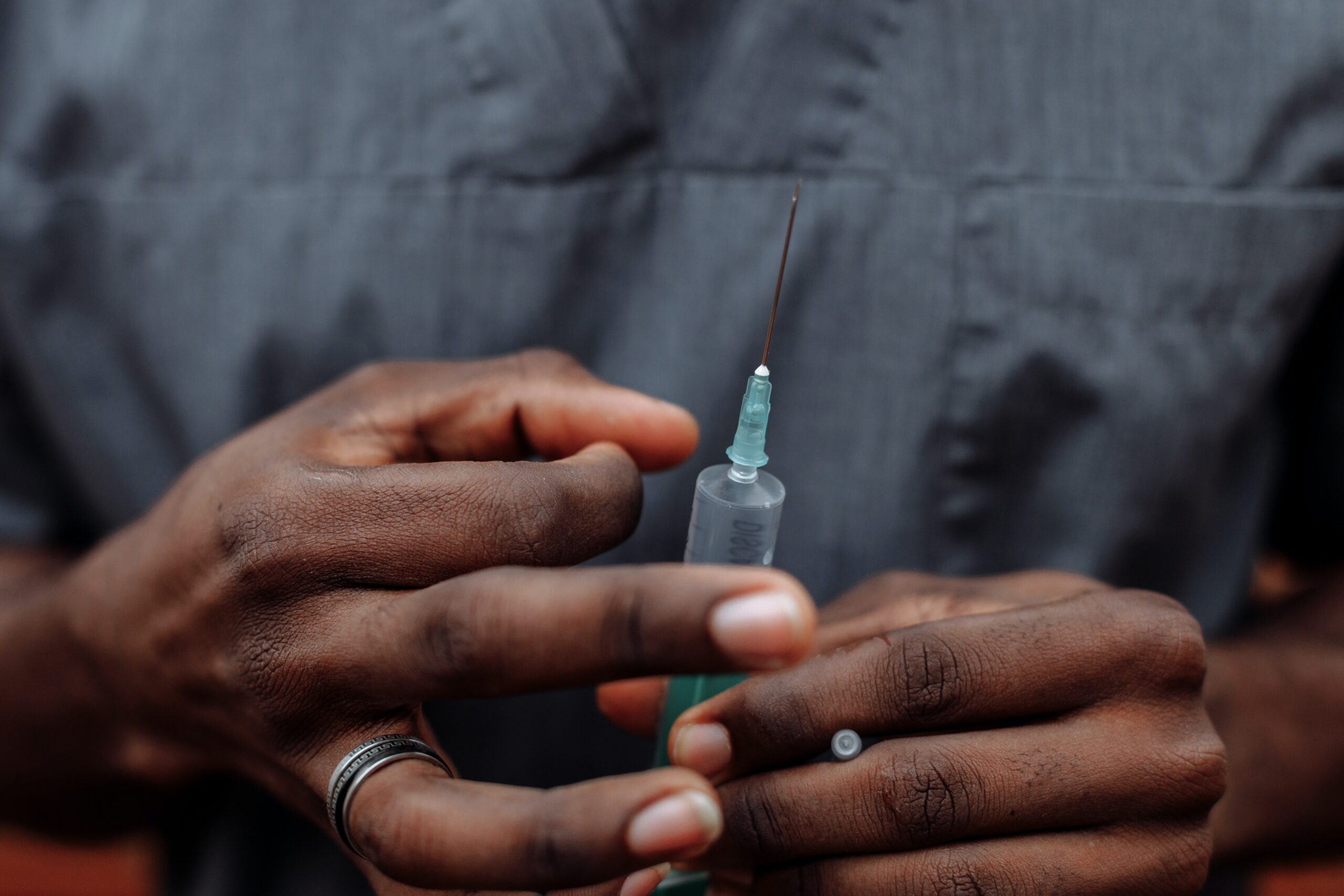 Person holding a syringe and vial, preparing an injection.