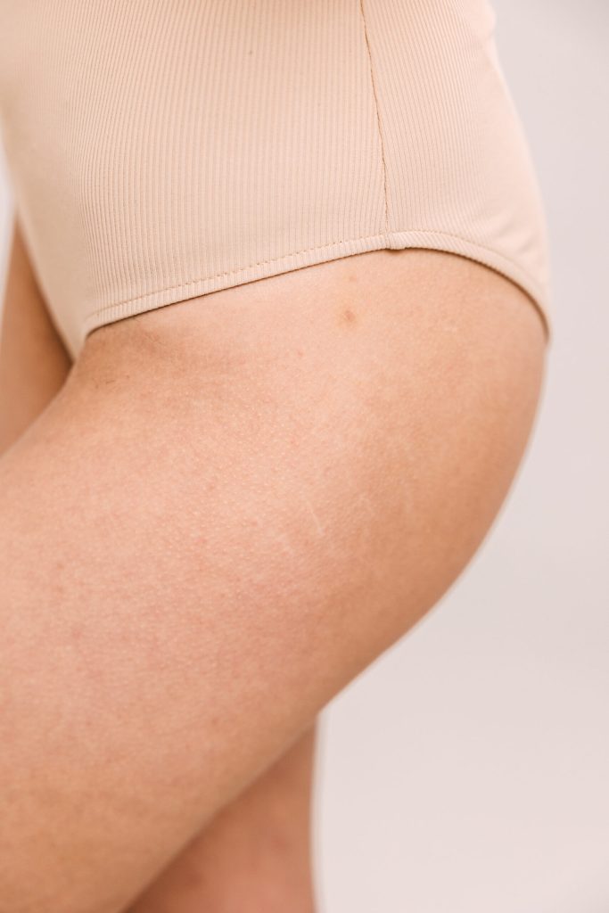 Close-up of a beige underwear-clad upper thigh and hip with visible skin texture.