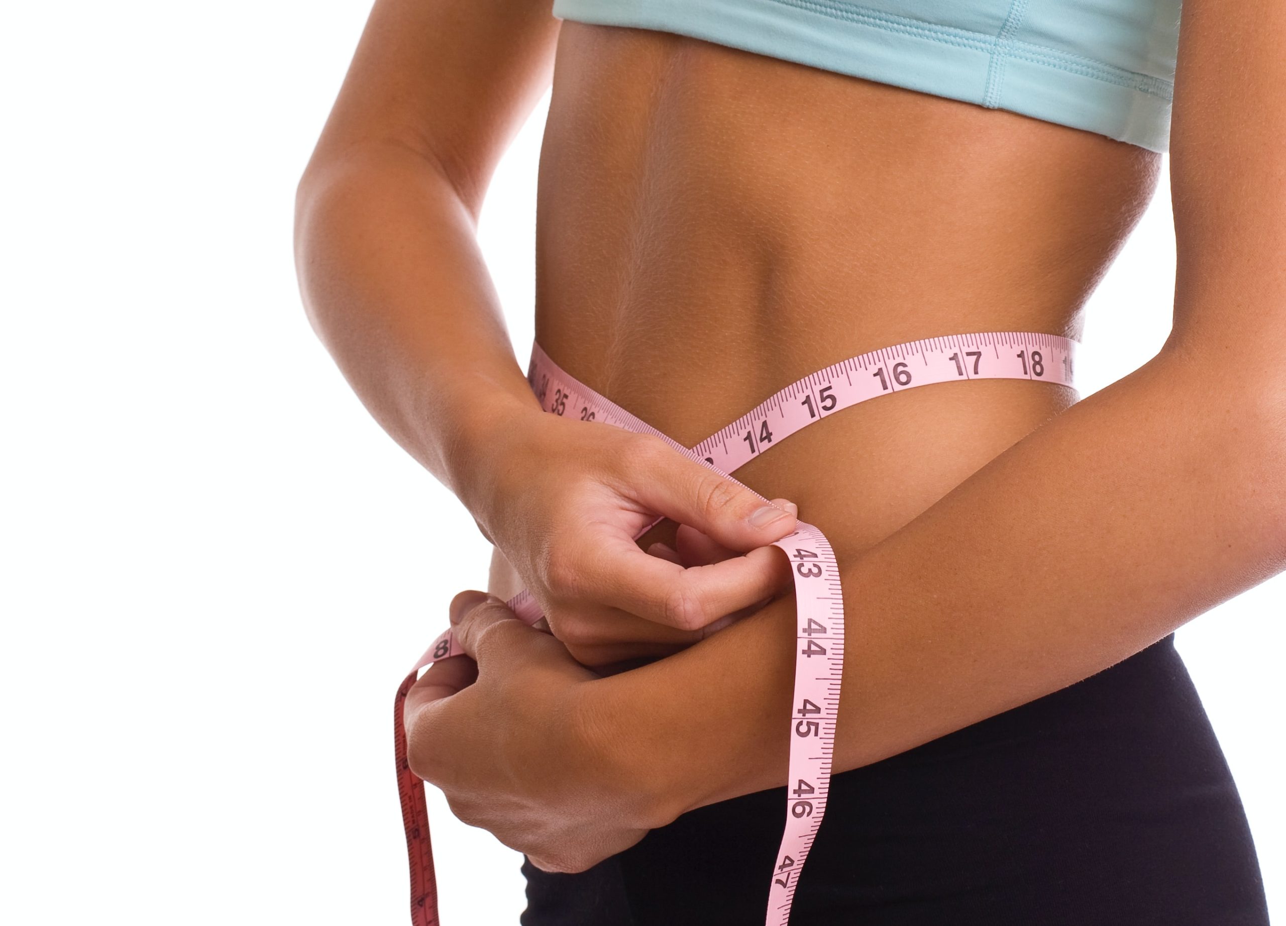 Person measuring waist with pink tape measure wrapped around midsection.